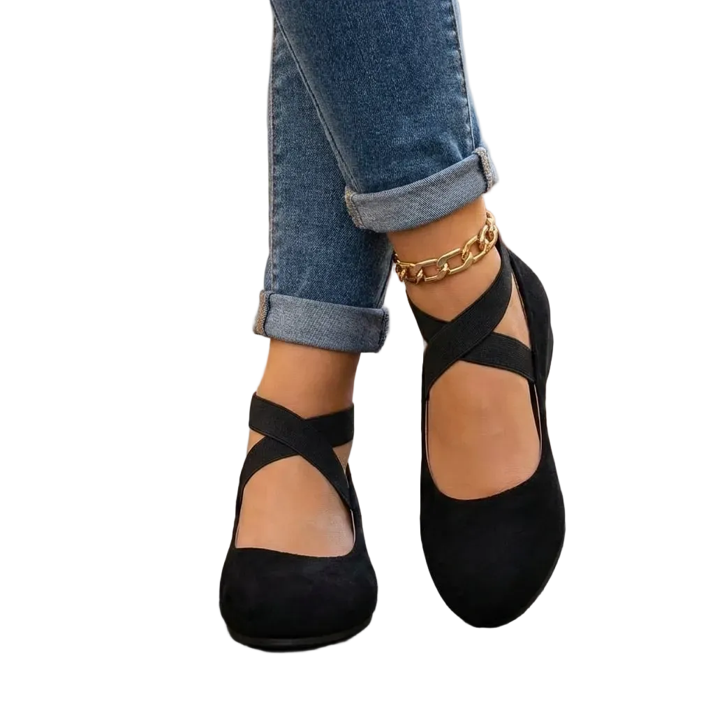 Black ballet flats worn with rolled-up jeans on a white background