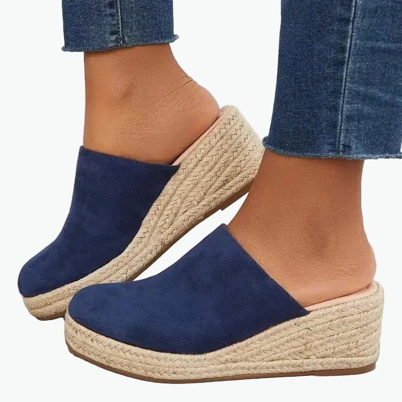 Blue suede espadrille wedge sandals with beige rope sole worn with blue jeans.