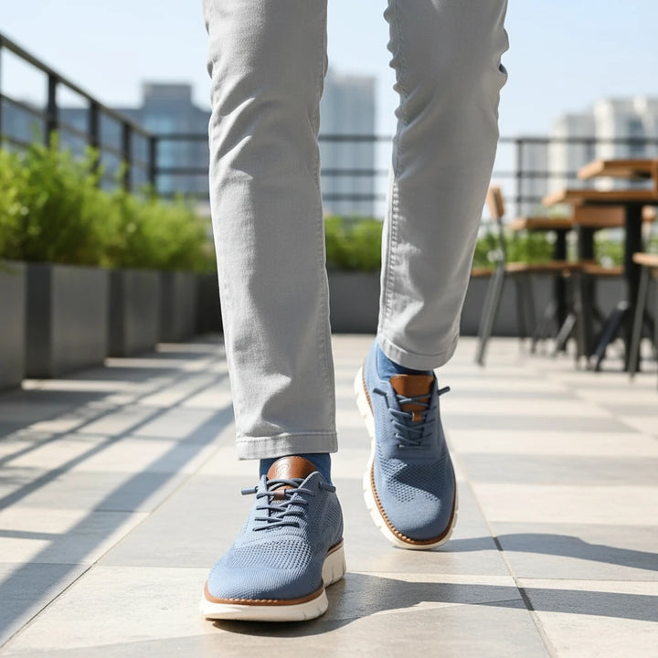 Person wearing blue sneakers with brown soles on a rooftop with plants and tables in the background.