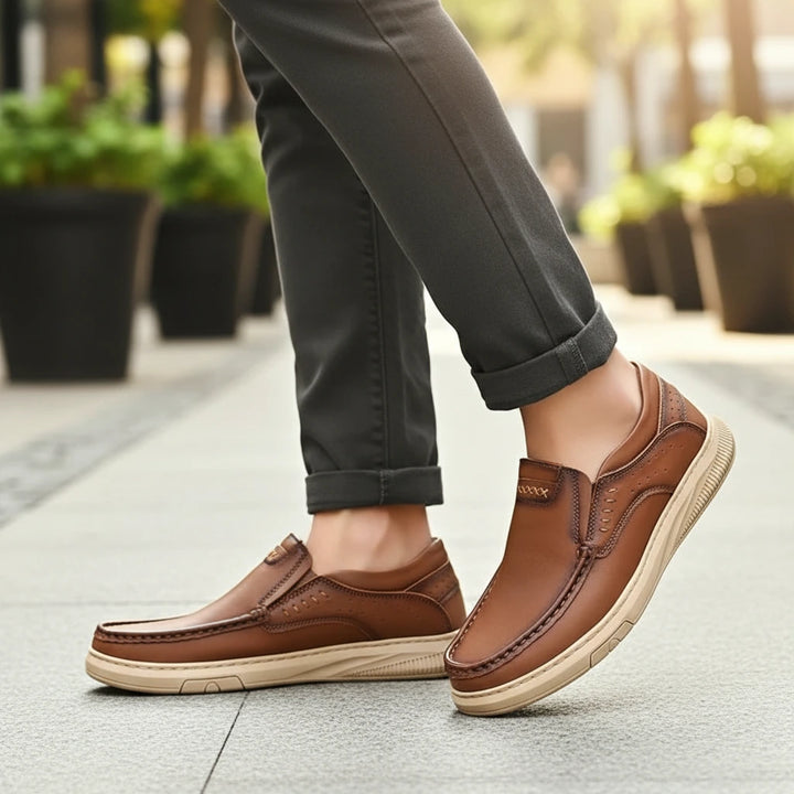 Brown leather shoes worn with rolled-up dark pants on a blurred outdoor background