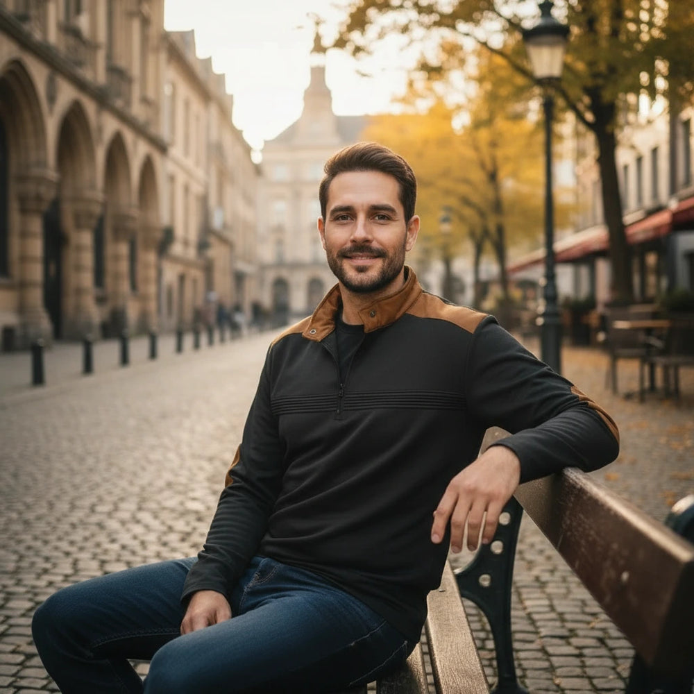 Man sitting on a bench in an urban setting with buildings and trees in the background