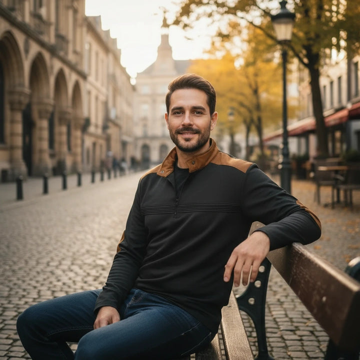 Man sitting on a bench in an urban setting with buildings and trees in the background